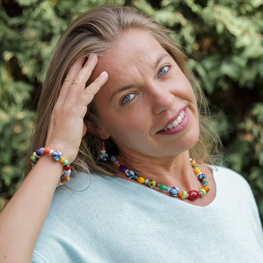 Woman wearing colorful jewelry with a green outdoor background